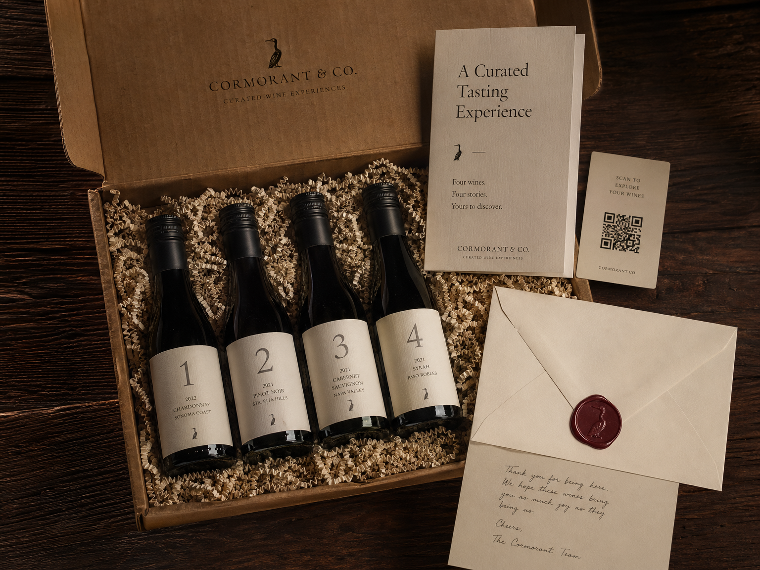 Overhead flat-lay of an opened BarrelTaster shipping box: four numbered sample bottles in cream crinkle paper, tasting card, QR code, wax-sealed envelope.